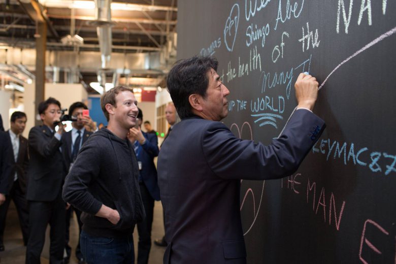 Mark Zuckerberg looking at what Japan´s prime minister Shinzo Abe is writing.