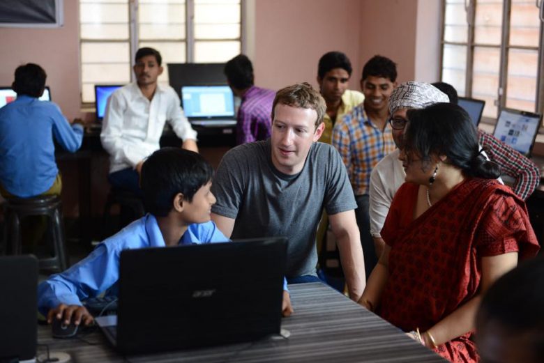 Mark Zuckerberg looking at the notebook screen of a student.