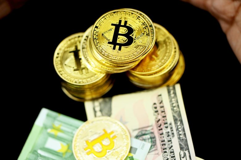 Bitcoin-Münzen und Dollar-Scheine. © Executium on Unsplash
