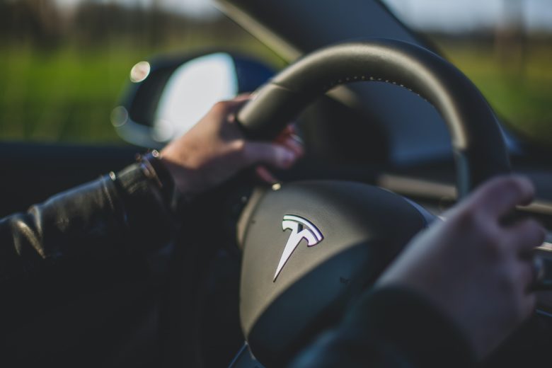 Tesla-Fahrer mit Händen am Steuer. © Bram Van Oost on Unsplash