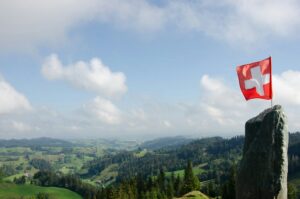 Schweizer Fahne weht über den Alpen. © Nadine Marfurt auf Unsplash
